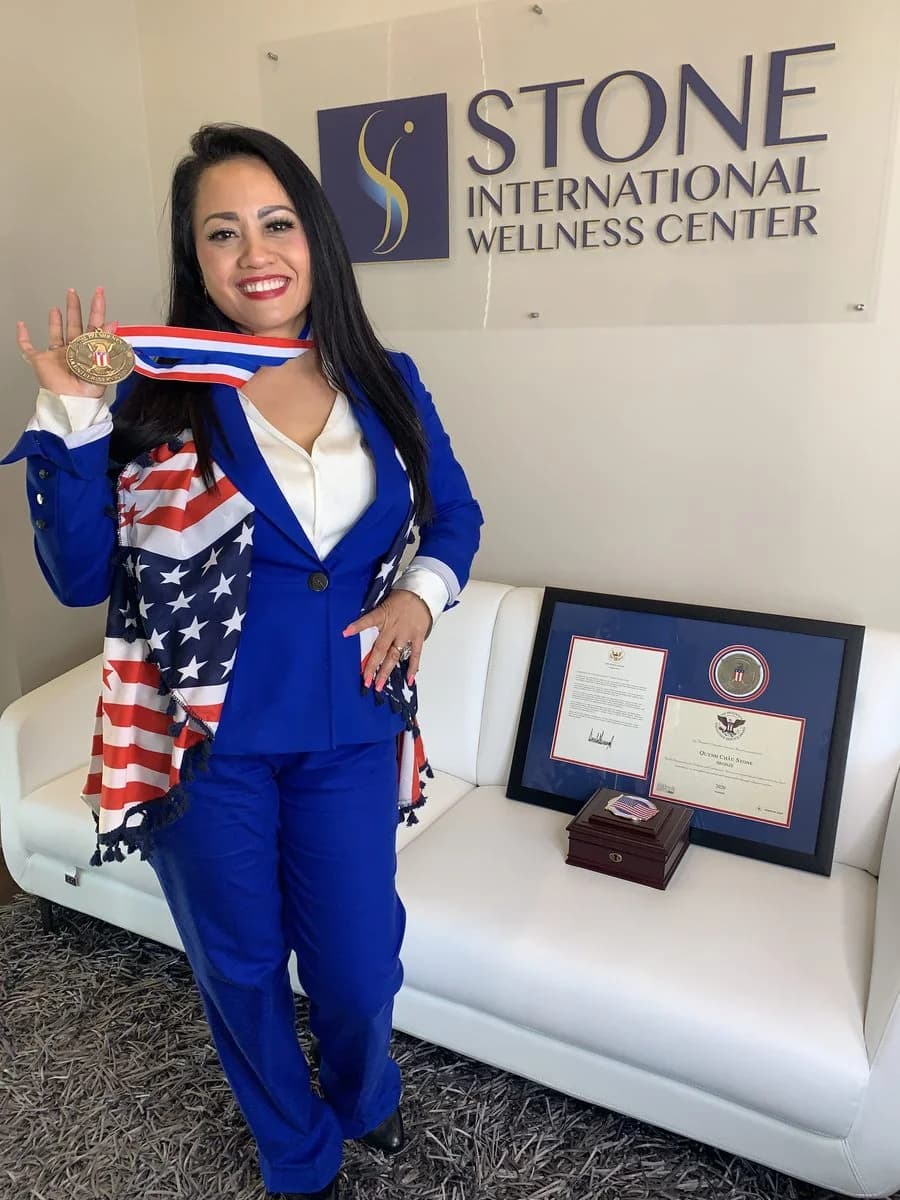 Quynh Chau Stone holding her 2020 Presidential Volunteer Service Award medal beside the framed certificate