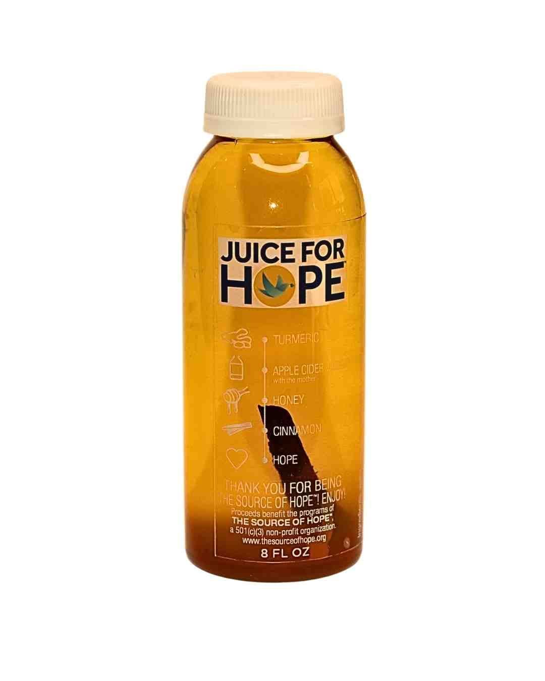8 oz plastic bottle of “Juice for Hope” wellness drink with a white cap, filled with golden liquid; label lists ingredients (turmeric, apple cider vinegar, honey, cinnamon) and notes proceeds support The Source of Hope nonprofit.